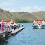 Tourists walking along a pier toward boats on Rinca Island in Komodo National Park