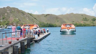Tourists walking along a pier toward boats on Rinca Island in Komodo National Park